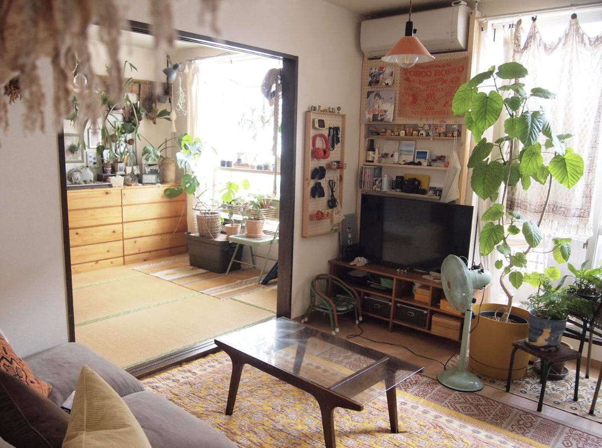 リビング。窓辺に植物、奥に襖を外した和室が見える